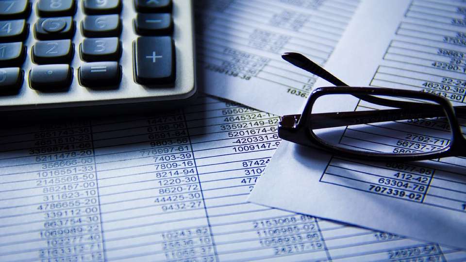 Calculator and glasses resting on printed spreadsheets