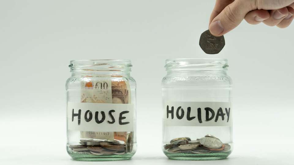 Coins going into jars labelled house and holiday